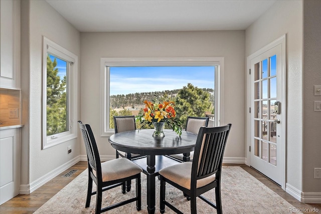 dining space with visible vents, plenty of natural light, baseboards, and wood finished floors