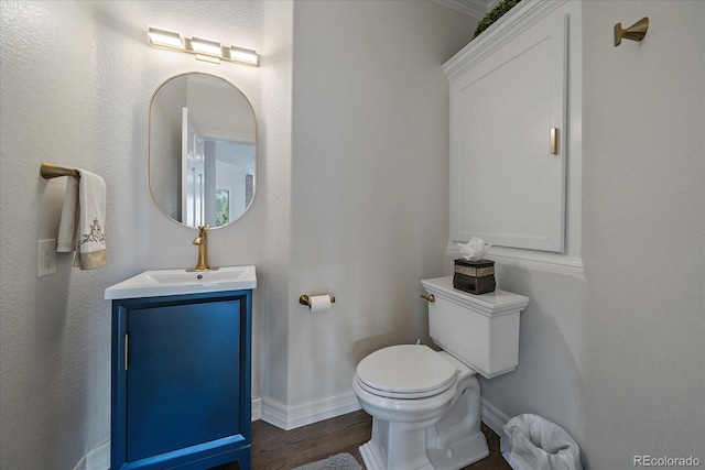 half bathroom featuring baseboards, toilet, wood finished floors, and vanity