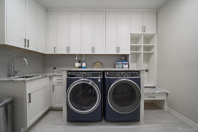 laundry room with a sink, cabinet space, baseboards, and separate washer and dryer