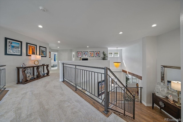 corridor with wood finished floors, recessed lighting, an upstairs landing, and baseboards