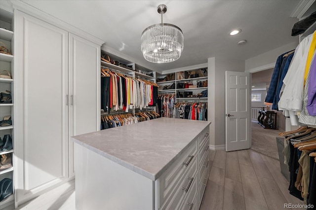 walk in closet featuring light wood-style flooring and a notable chandelier