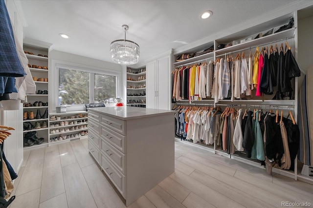 walk in closet featuring an inviting chandelier and light wood-style flooring