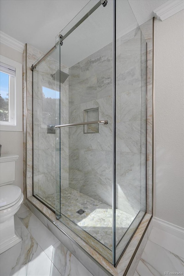 bathroom with crown molding, toilet, marble finish floor, and a stall shower