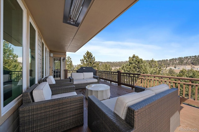 view of wooden balcony featuring a wooden deck, a forest view, and an outdoor hangout area