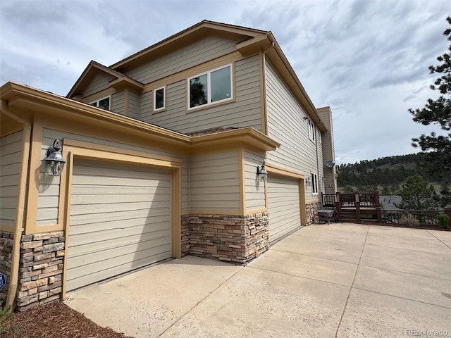 1366 Killington Ct, Evergreen, CO 80439 - view of side of property featuring stone siding, driveway, and an attached garage