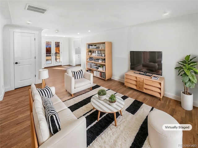 living room with recessed lighting, visible vents, baseboards, and wood finished floors