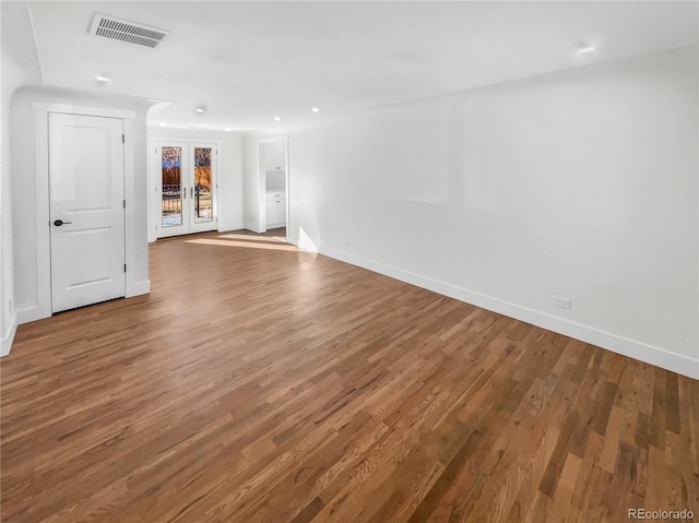 spare room with visible vents, french doors, baseboards, and wood finished floors