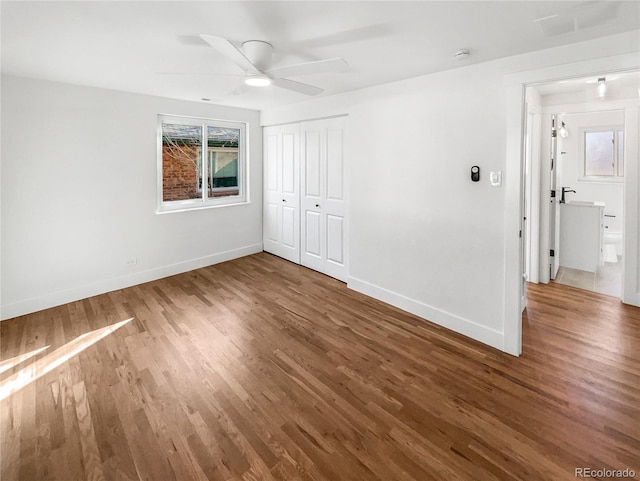 unfurnished bedroom with ceiling fan, a closet, baseboards, and wood finished floors