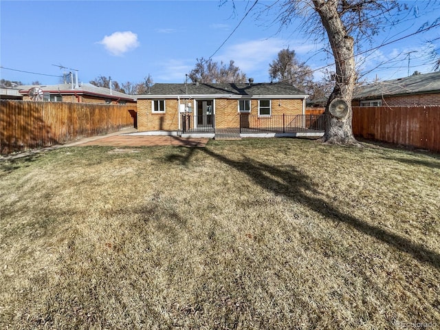 back of house with brick siding, a patio, a fenced backyard, and a lawn