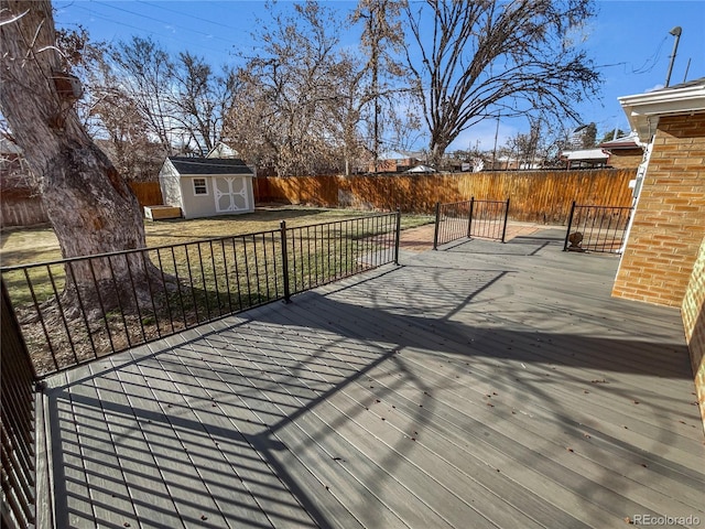 wooden terrace with an outbuilding, a storage unit, and a fenced backyard