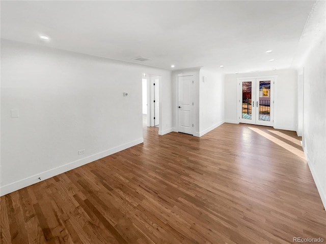 spare room with wood finished floors, french doors, baseboards, and visible vents