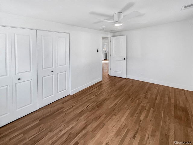 unfurnished bedroom featuring a closet, visible vents, baseboards, and wood finished floors