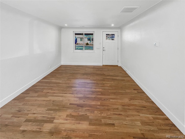 unfurnished room with recessed lighting, wood finished floors, visible vents, and baseboards