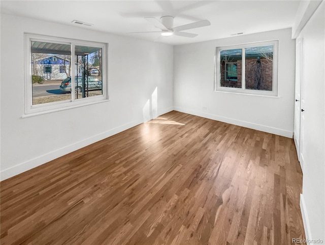 unfurnished room with ceiling fan, visible vents, baseboards, and wood finished floors