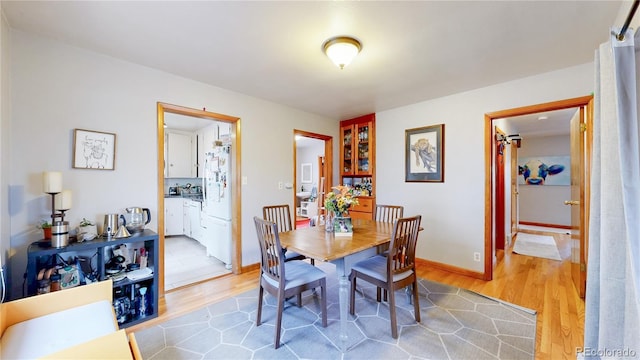 dining space with baseboards and light wood-style flooring