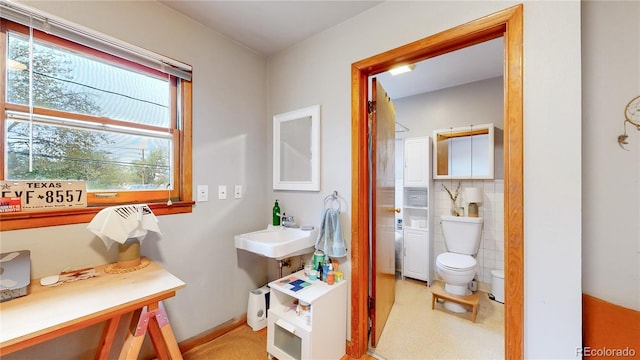 bathroom featuring a sink, tile walls, and toilet