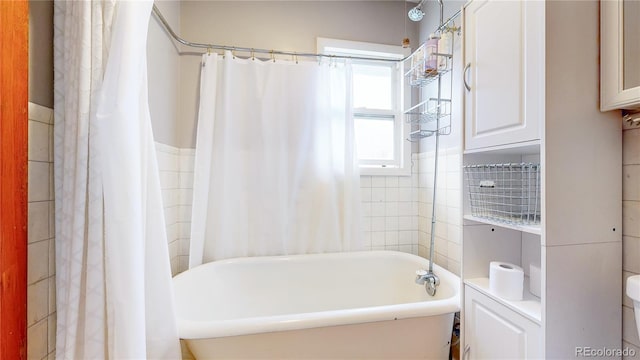 full bathroom with wainscoting and tile walls