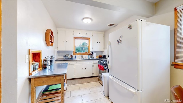 kitchen featuring backsplash, visible vents, white cabinetry, freestanding refrigerator, and light tile patterned flooring