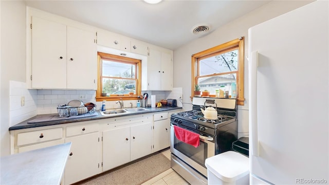 kitchen with freestanding refrigerator, a wealth of natural light, a sink, and stainless steel gas stove