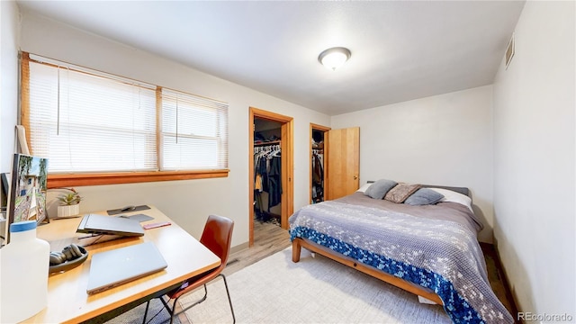 bedroom featuring a closet, a walk in closet, wood finished floors, and visible vents