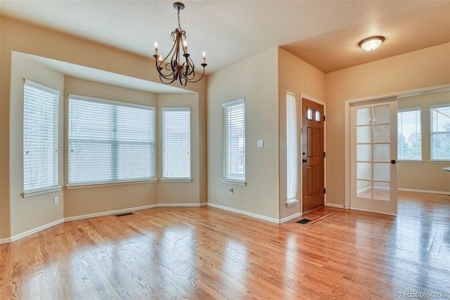 entryway with an inviting chandelier, plenty of natural light, and light hardwood / wood-style floors