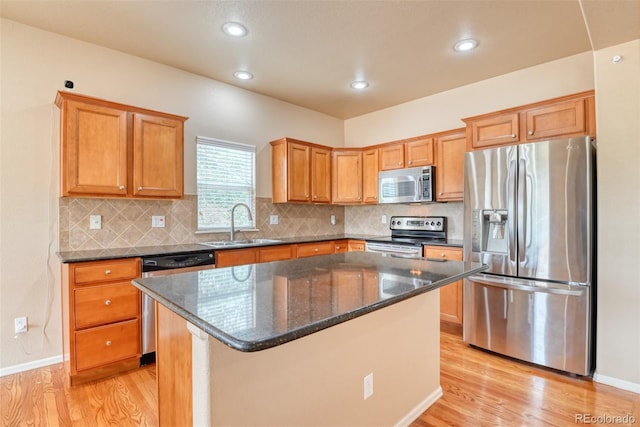 kitchen featuring a kitchen island, appliances with stainless steel finishes, sink, and light hardwood / wood-style flooring