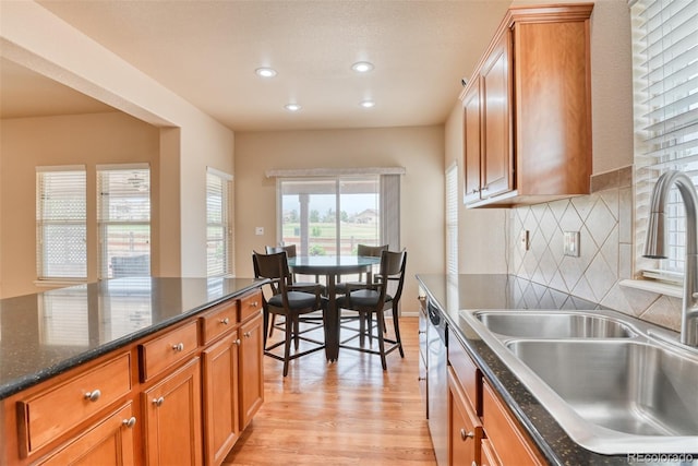 kitchen with dark stone countertops, sink, tasteful backsplash, and light wood-type flooring