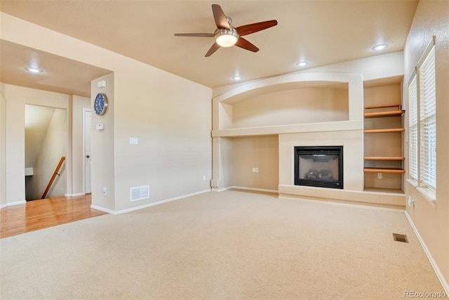 unfurnished living room with carpet, ceiling fan, and built in shelves