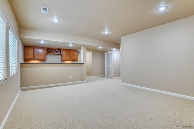 unfurnished living room featuring indoor bar, plenty of natural light, and light colored carpet