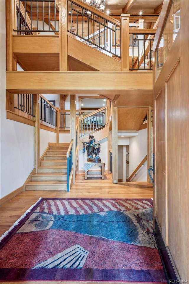 stairs with beam ceiling, a towering ceiling, and hardwood / wood-style flooring