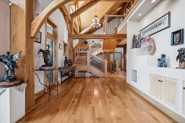 interior space featuring light hardwood / wood-style flooring, high vaulted ceiling, beam ceiling, wooden ceiling, and a chandelier