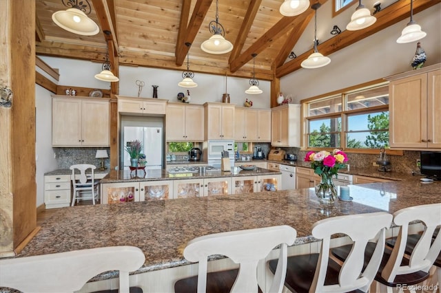 kitchen featuring white refrigerator, decorative light fixtures, and dark stone counters