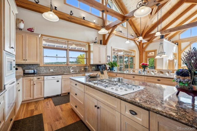 kitchen with hanging light fixtures, beamed ceiling, white appliances, decorative backsplash, and light wood-type flooring