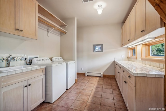 clothes washing area with cabinets, a baseboard heating unit, sink, light tile patterned floors, and independent washer and dryer