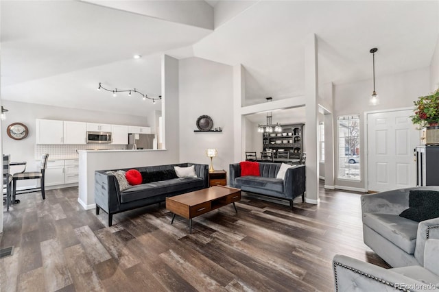 living room featuring an inviting chandelier, vaulted ceiling, and dark wood-type flooring