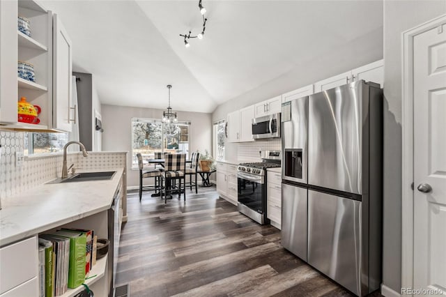 kitchen with white cabinets, sink, light stone countertops, appliances with stainless steel finishes, and decorative light fixtures