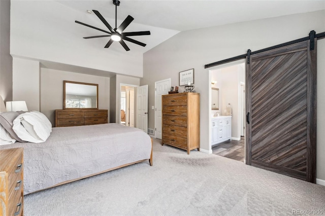 carpeted bedroom featuring ceiling fan, a barn door, connected bathroom, and vaulted ceiling