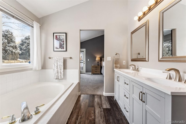 bathroom featuring vanity, a relaxing tiled tub, lofted ceiling, and hardwood / wood-style flooring