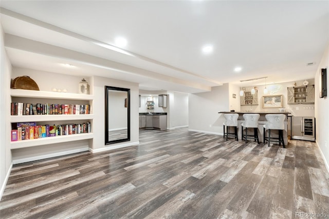 living room featuring built in shelves, dark hardwood / wood-style flooring, wine cooler, and bar