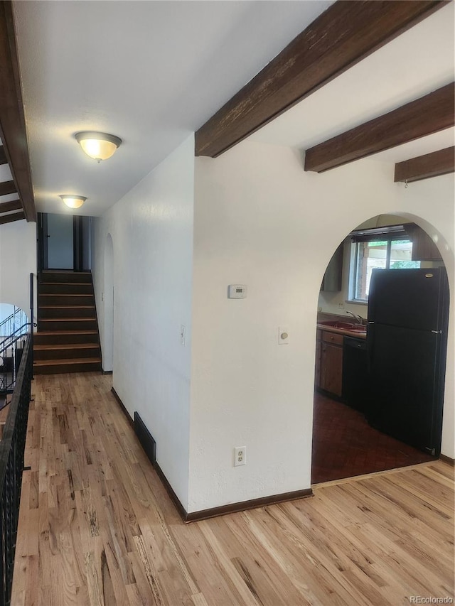 hall featuring light wood-type flooring and beamed ceiling