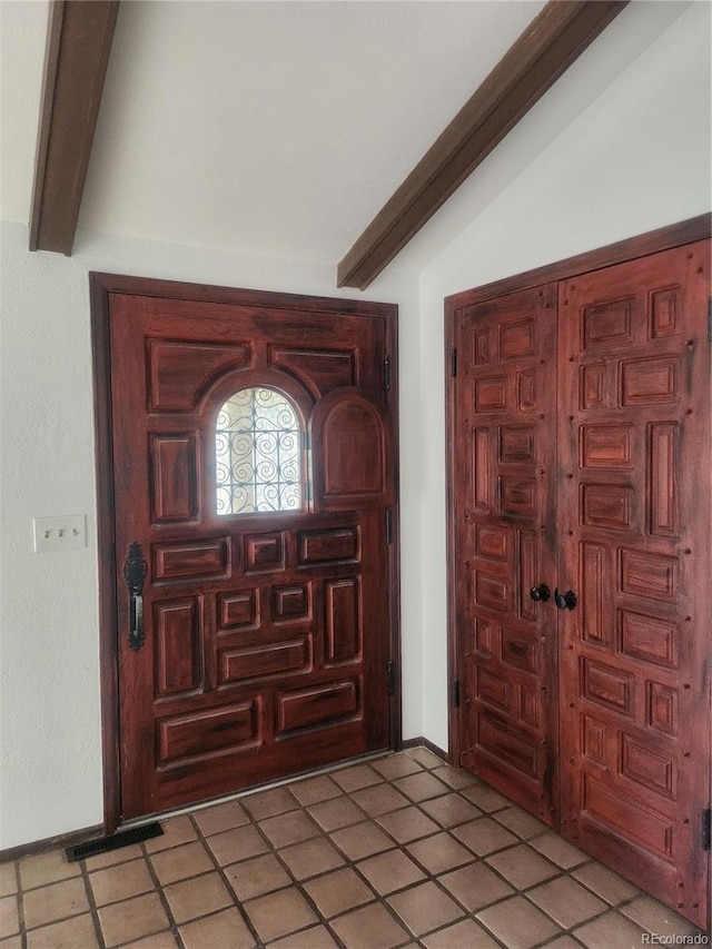 tiled foyer entrance with vaulted ceiling with beams