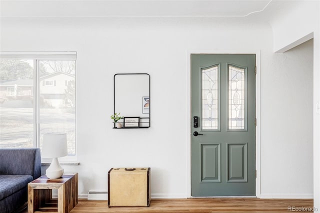 entryway with a baseboard heating unit, light wood-style flooring, and baseboards