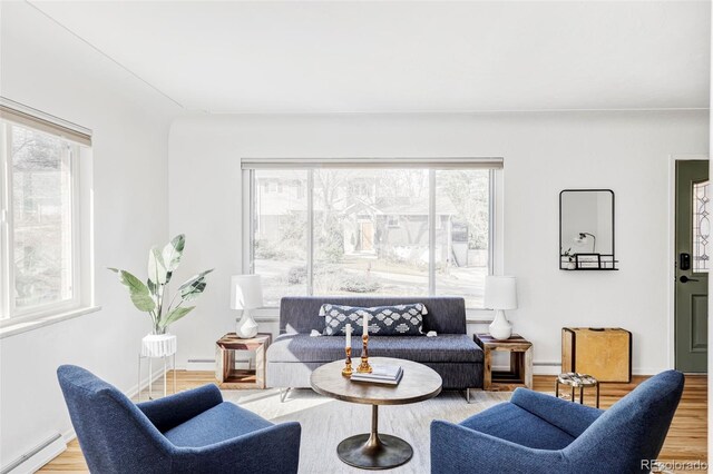 living area featuring a baseboard heating unit, baseboards, and wood finished floors