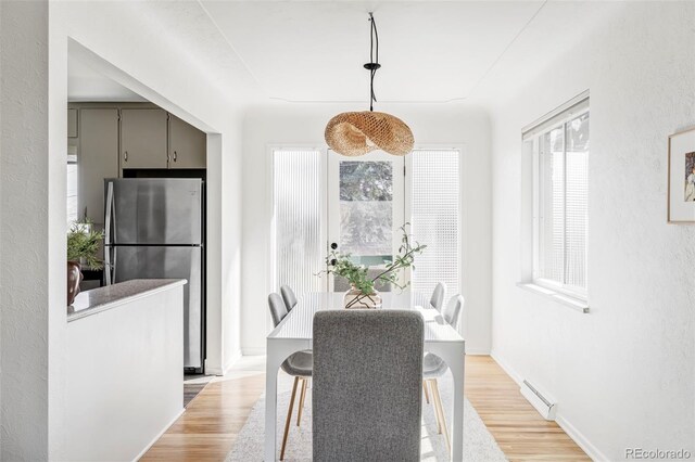 dining space featuring a textured wall, light wood finished floors, visible vents, and baseboards