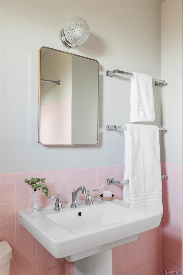 bathroom with wainscoting, a sink, tile walls, and toilet