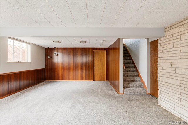 basement featuring wood walls, carpet, stairs, and wainscoting