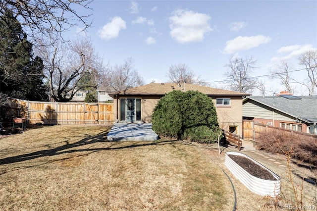 rear view of house with brick siding, fence, and a lawn