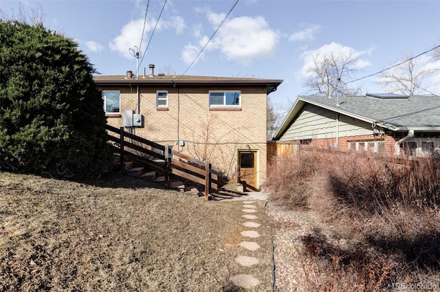 back of property featuring brick siding and fence