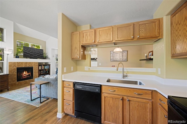 12812 Jasmine St Unit C, Thornton, CO 80602 - kitchen with black dishwasher, light wood finished floors, light countertops, a tile fireplace, and open floor plan