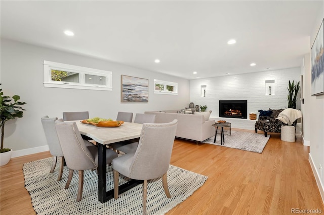 dining area with a healthy amount of sunlight, a fireplace, and light hardwood / wood-style flooring